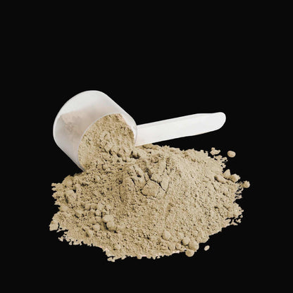 Protein powder scoop with beige fine powder spilling over black surface, smooth texture and lightweight appearance